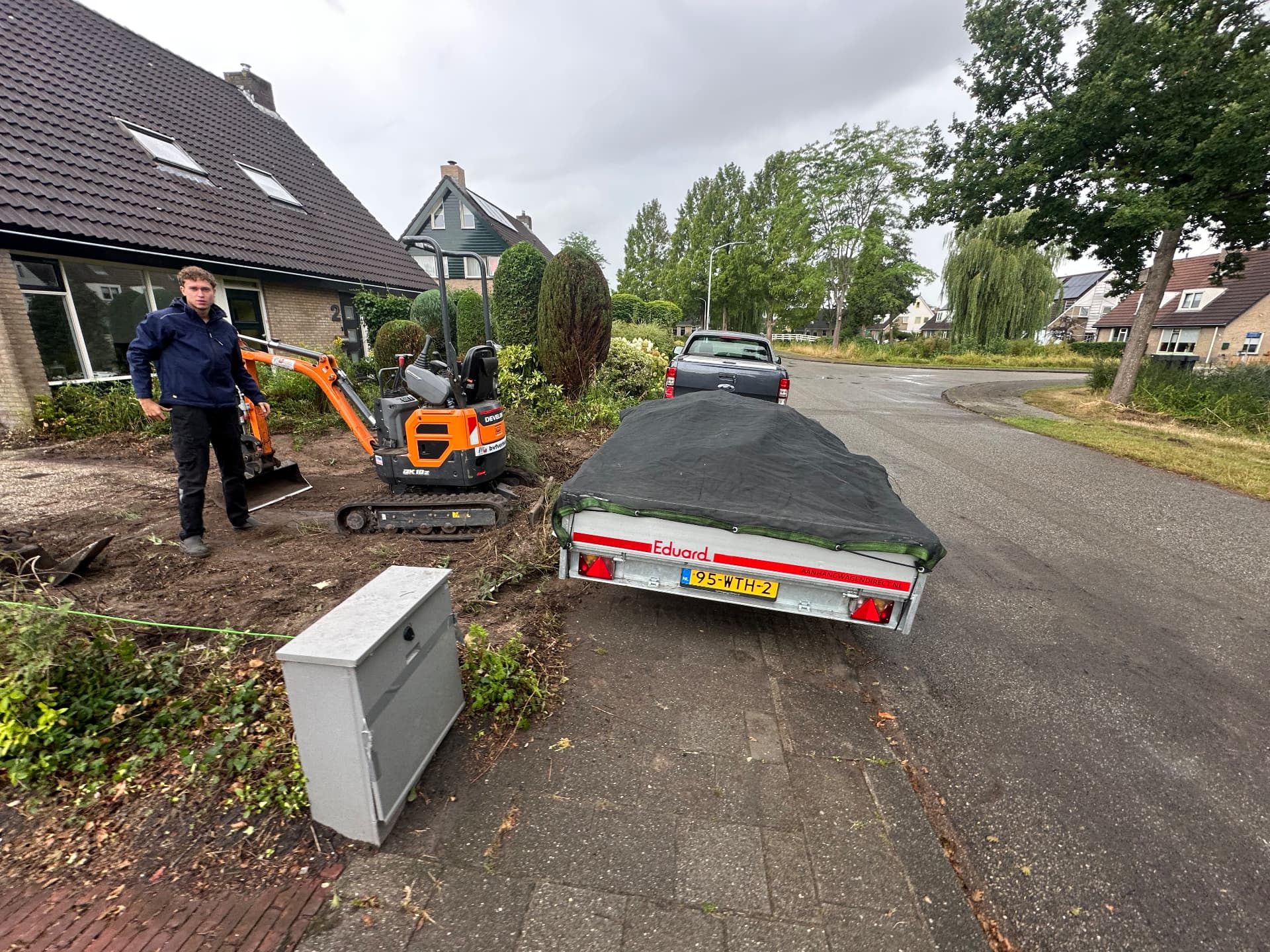 Minigraver en aanhanger bij rooi- en grondwerk voor een voortuin